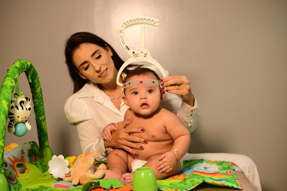 Karla Portela realizando avaliação de osteopatia pediátrica em bebê